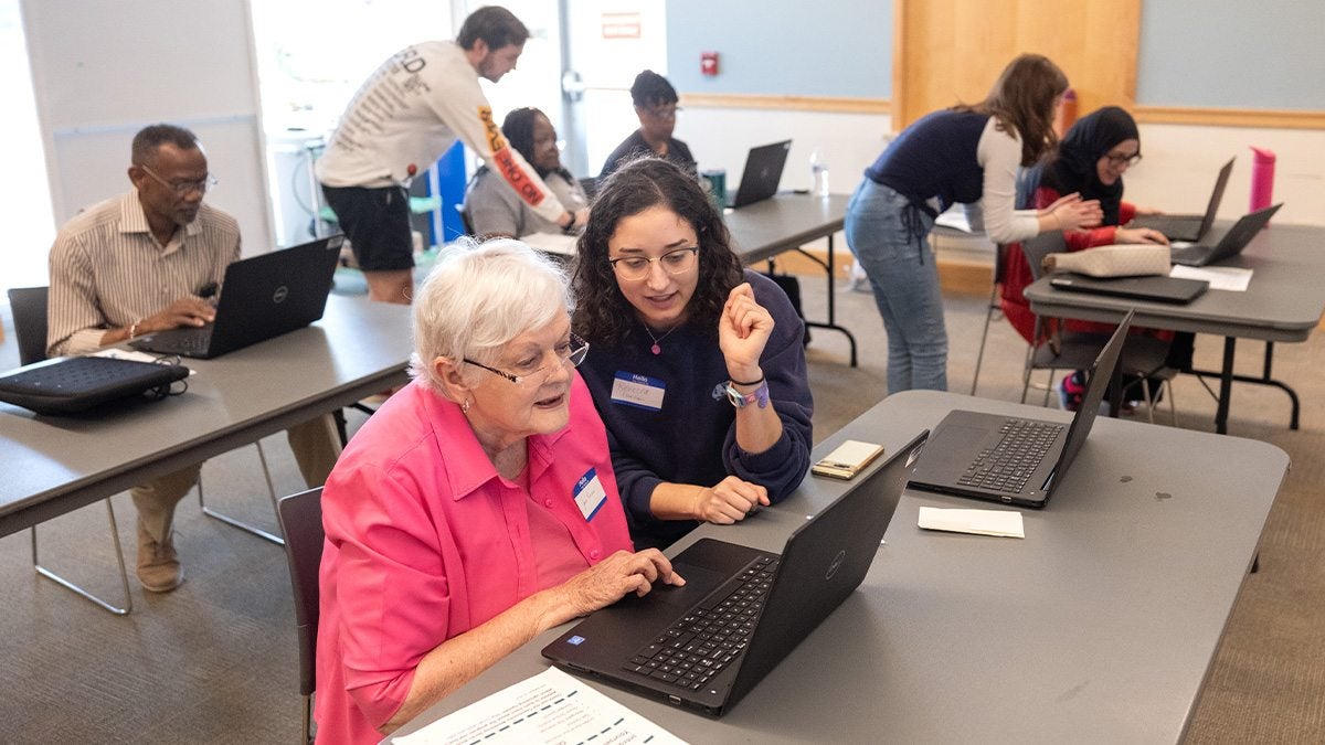 Community digital literacy class with mentor and learner at a laptop